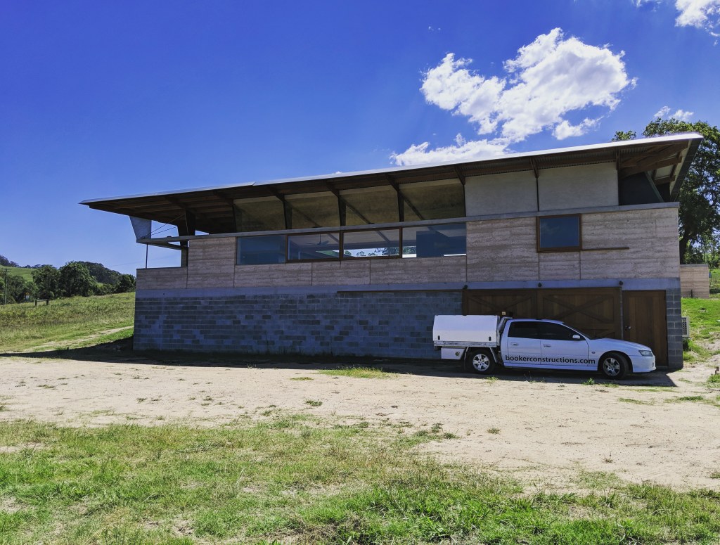 "Exterior view of Sacred Mountain House by Booker Constructions, featuring rammed earth walls and timber structure."